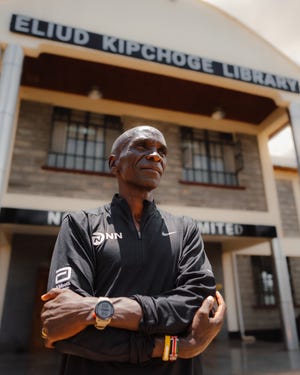 eliud kipchoge standing in front of the eliud kipchoge library a structure characterized by a prominent sign displaying its name