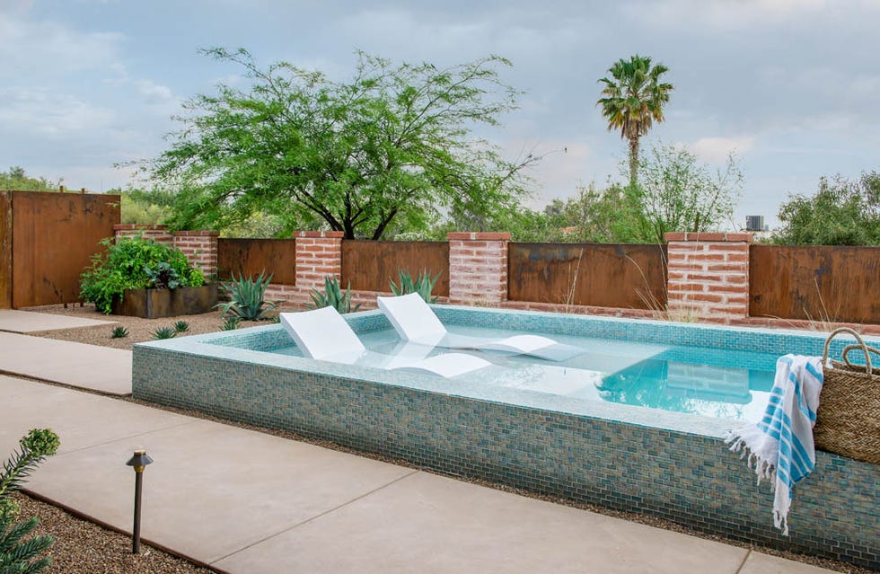 a swimming pool with a brick wall and a tree in the background
