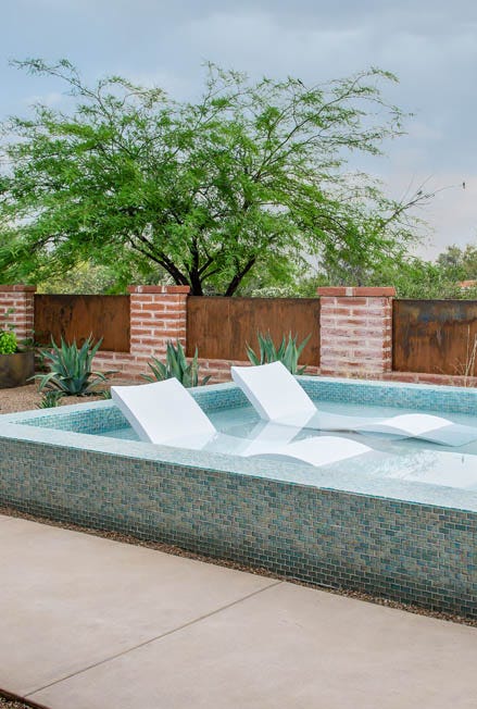 a swimming pool with a brick wall and a tree in the background a swimming pool with a brick wall and a tree in the background