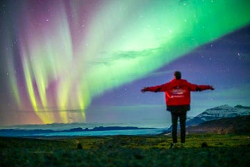 een man kijkt naar het noorderlicht in ijsland