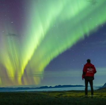 een foto van een man die kijkt naar het noorderlicht op ijsland