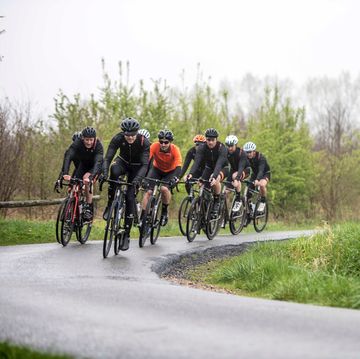 een groep wielrenners fietst in de regen