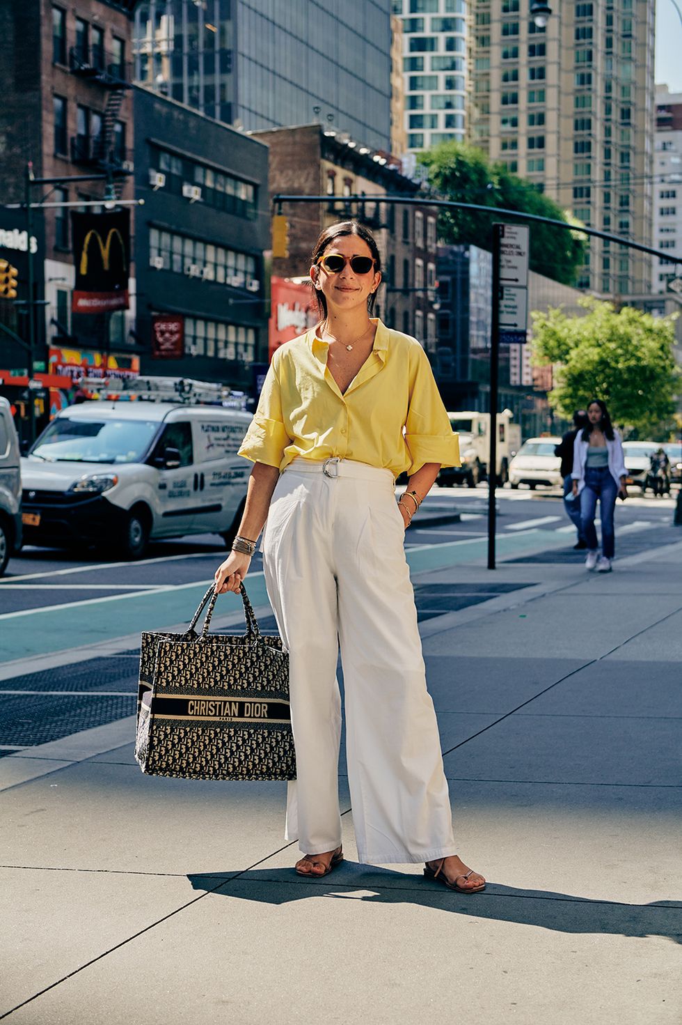 a bazaar staffer wears a button down shirt and pants with a dior bag to illustrate a guide to work outfit ideas 2022