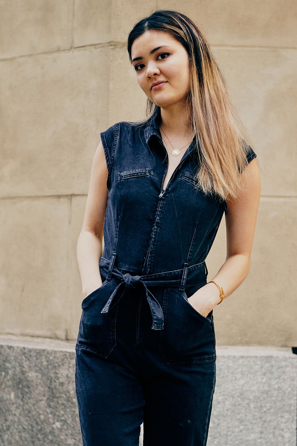 a bazaar staffer wears a denim jumpsuit to illustrate a guide to work outfit ideas 2022