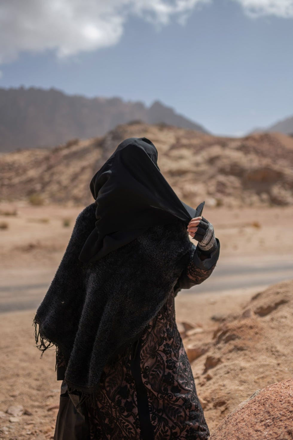 Een vrouw trotseert de wind terwijl ze wacht totdat ze in de dorpskliniek aan de beurt is In het kader van een dorpsproject wordt originele pozie die door mannen is geschreven gecombineerd met fotos Pozie van Seliman Abdel Rahman Aboe Anas Foto en Arabische vertaling van het gedicht door Rehab Eldalil