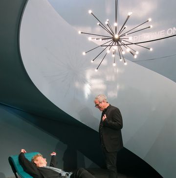 a person standing on a person lying on a chair in a room with lights