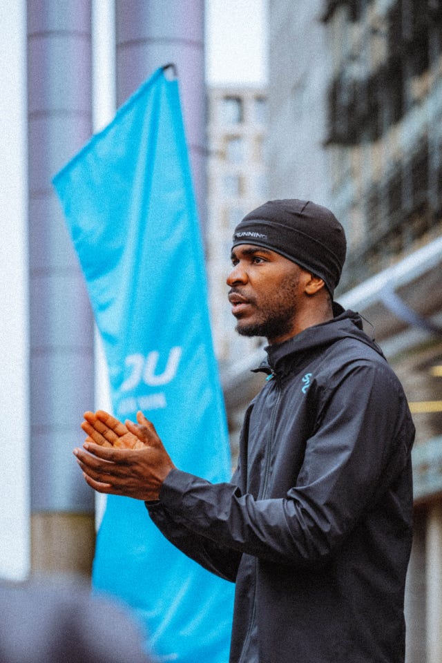 runner wearing a waterproof jacket and beanie hat beside a banner