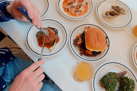 a dining table setting with various dishes and a person preparing to eat