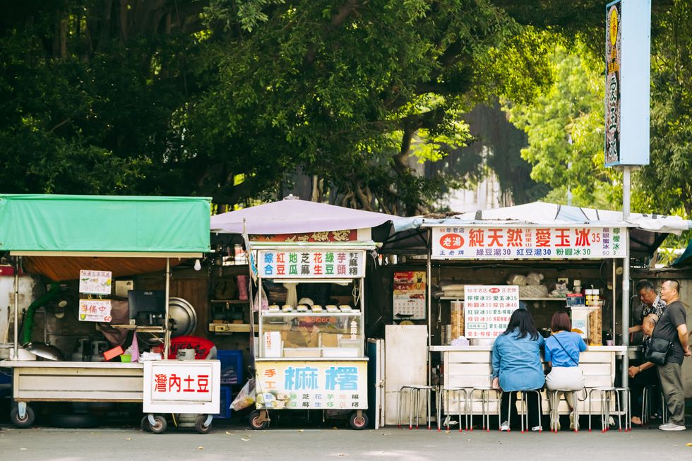 a group of people stand outside of a food stand