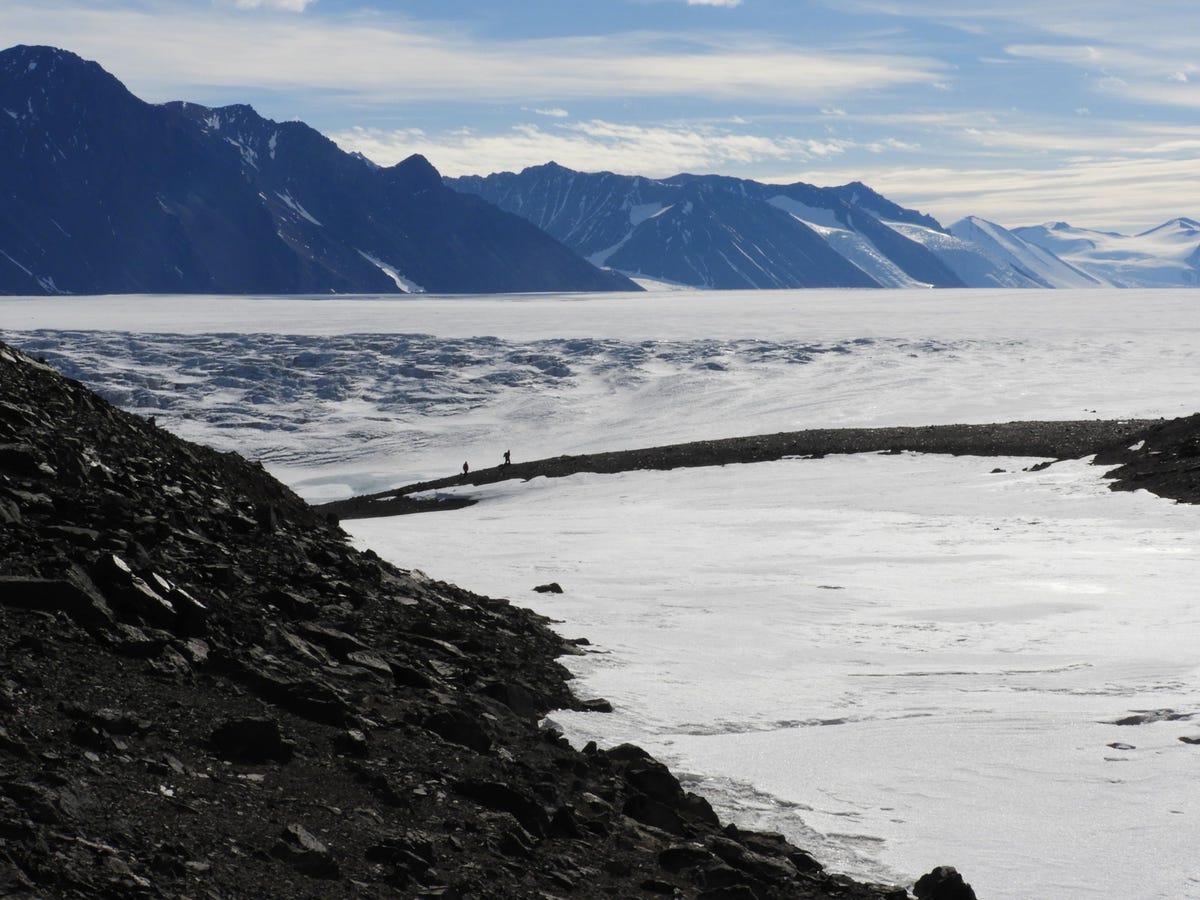 Twee leden van het expeditieteam gaan op weg om bodemmonsters te nemen op een van de onderzoekslocaties rond de Shackleton Glacier