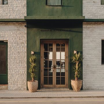 groen met witte voorgevel van hotel met houten deuren en palmen