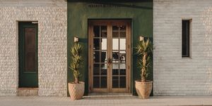 groen met witte voorgevel van hotel met houten deuren en palmen