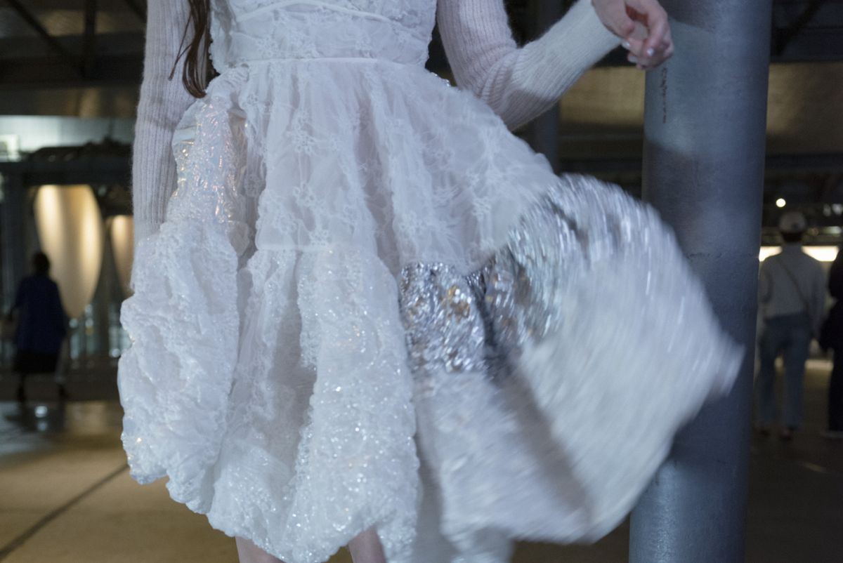 a model wears cecilie bahnsen asics sneakers with a white embellished dress coated in sequins