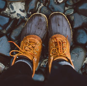 person wearing duck boots on top of wet rocks