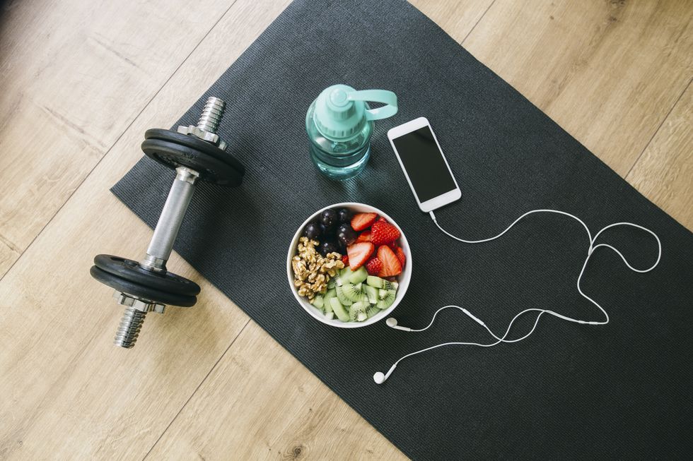 dumbbell, drinking bottle, fruit bowl and smartphone with earphones