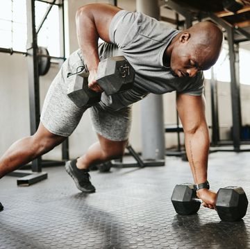 dumbbell, fitness and bodybuilder black man with workout training in gym or garage studio for wellness, body goal and motivation power, strong and african sports man doing push up exercise with gear