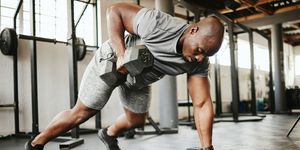 dumbbell, fitness and bodybuilder black man with workout training in gym or garage studio for wellness, body goal and motivation power, strong and african sports man doing push up exercise with gear