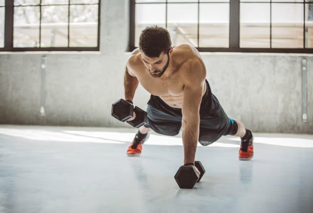 strong young man in gym performing push ups with weighs