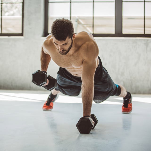 strong young man in gym performing push ups with weighs