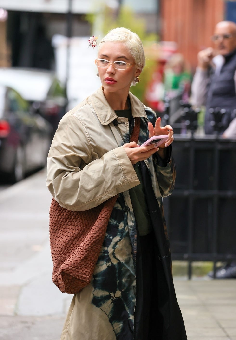Persona de pie en la calle usando un teléfono inteligente mientras usa un atuendo elegante