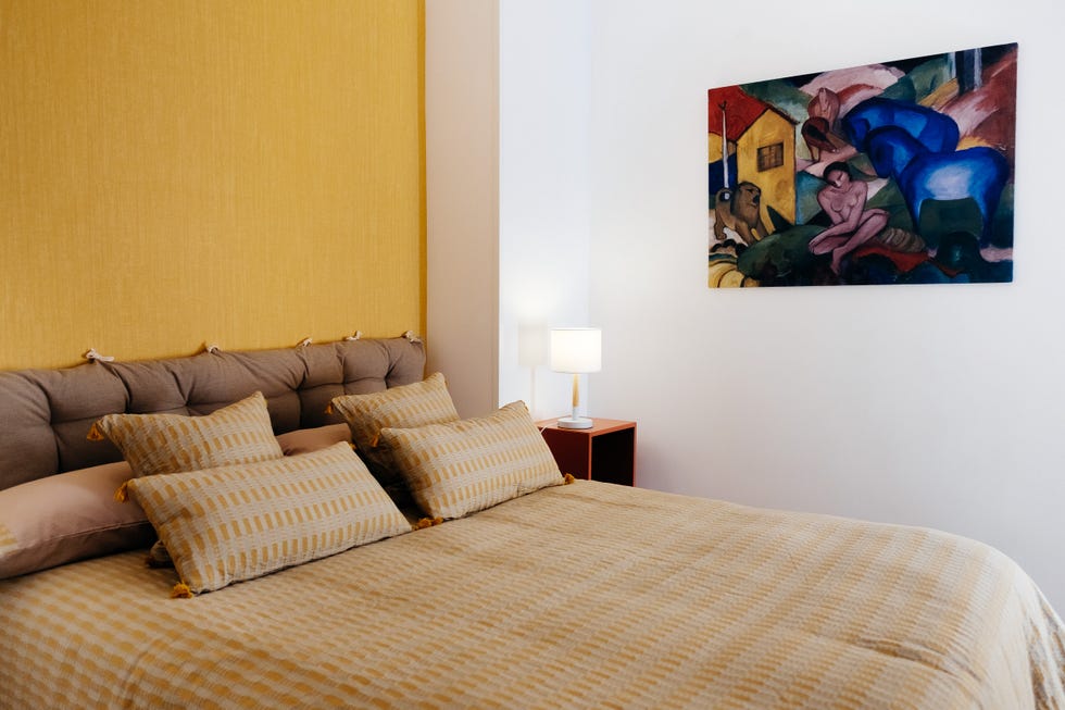 dormitorio con cabecero acolchado marrón y pared del cabecero con papel pintado amarillo