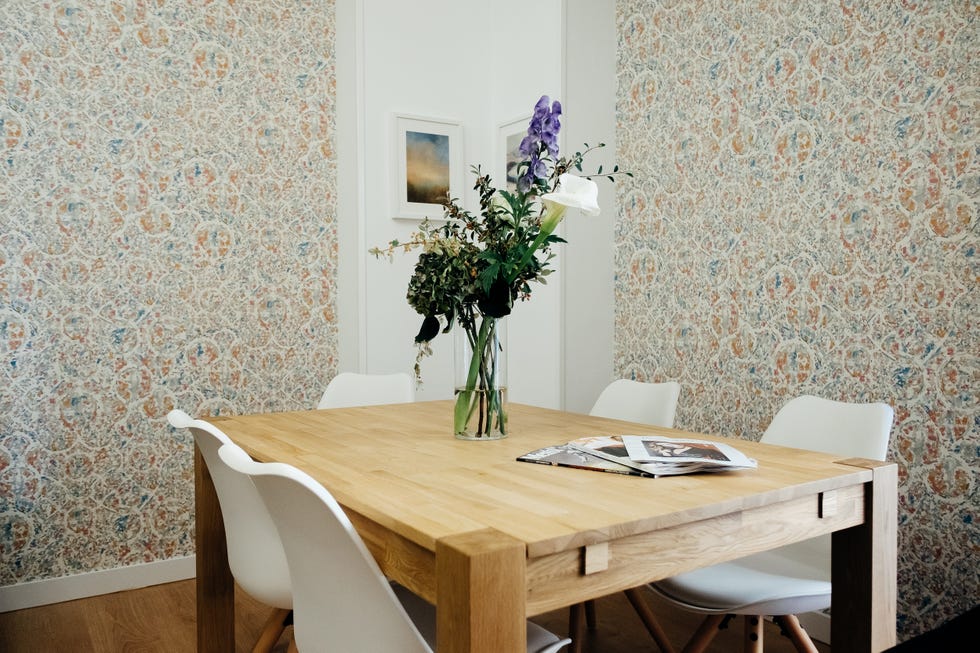comedor con mesa de madera, sillas nórdicas y papel pintado con motivos abstractos de colores