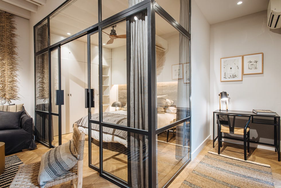 dormitorio con cerramiento de vidrio y metal decorado con fibras y madera y escritorio anexo