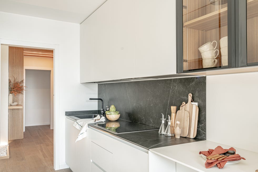 cocina blanca con frentes lisos y encimera de piedra negra