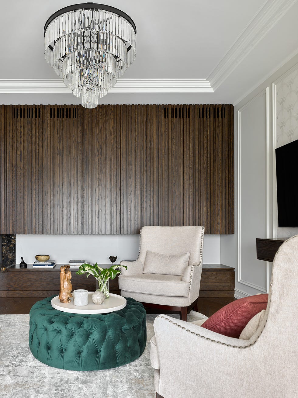 salón de estilo clásico con mesa de centro de terciopelo verde capitoné y butacas tapizadas en color beige