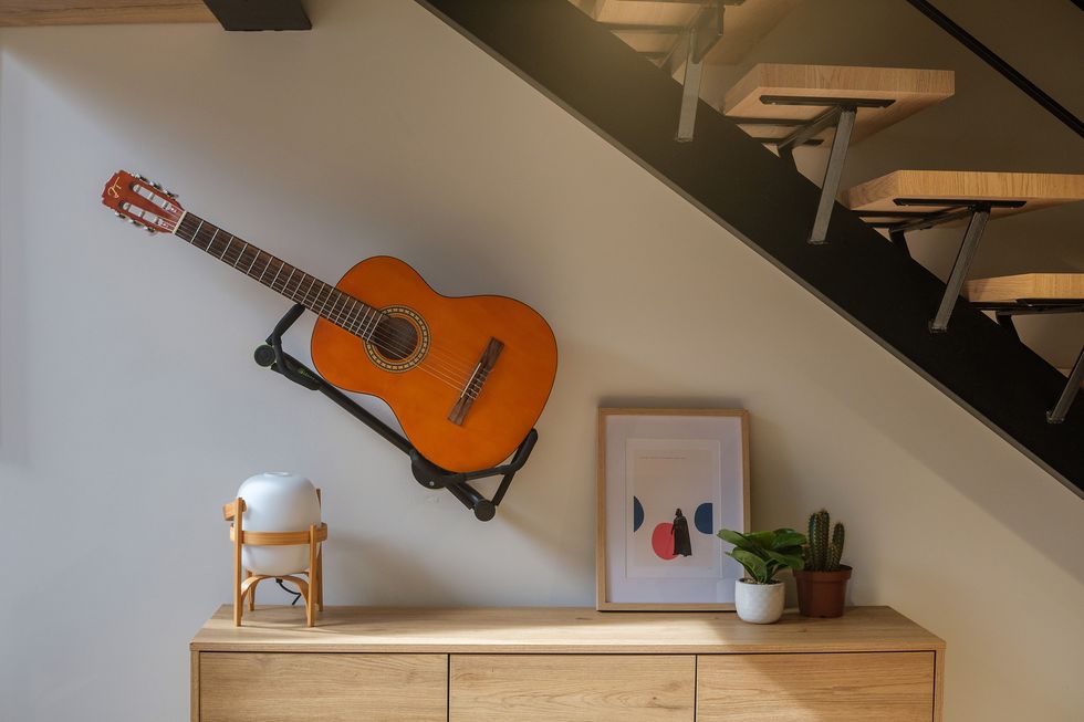 cómoda de madera y guitarra en la pared