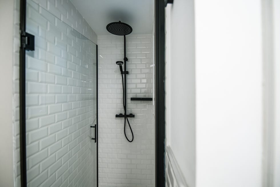 ducha revestida con azulejos tipo metro en color blanco y grifería negra