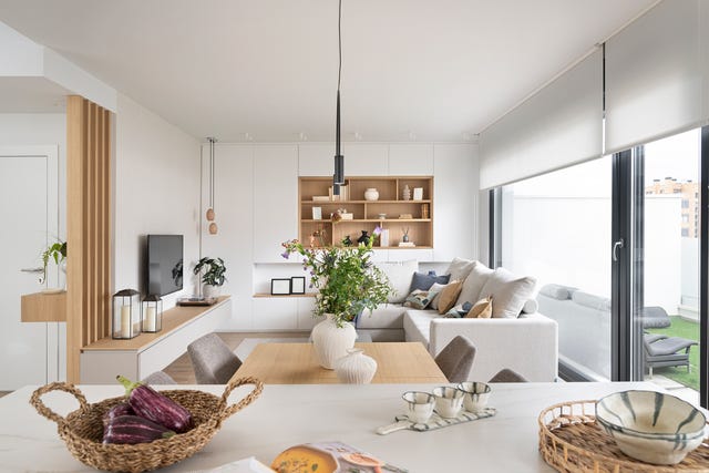 salón comedor con sofá beige y estantería en blanco y madera