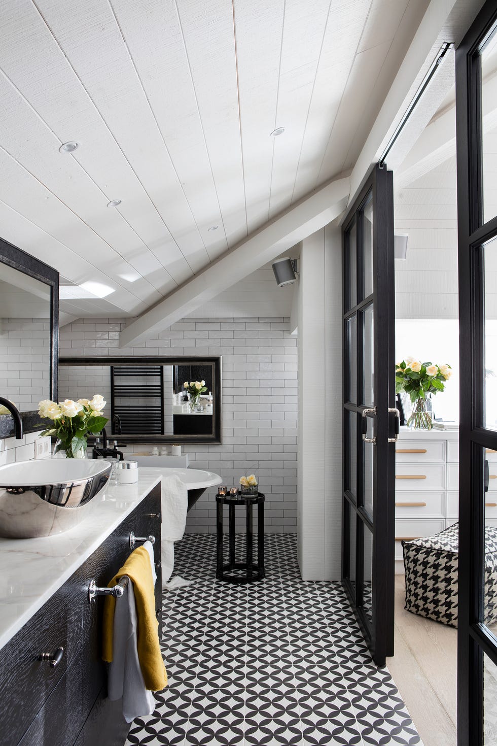 baño con azulejos geométricos en blanco y negro y paredes de azulejos blancos tipo metro