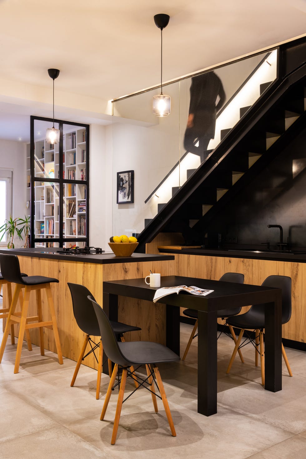 Cocina con office y escalera decoradas en negro y madera