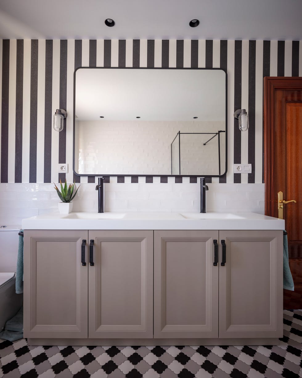 baño con mueble en color visón y papel pintado a rayas en las paredes