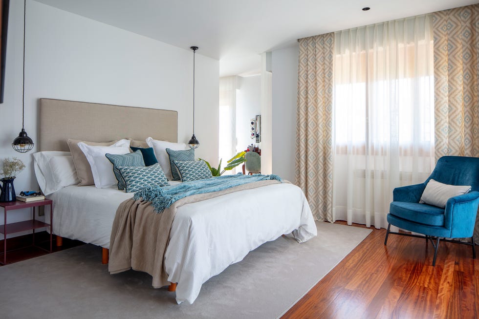 cama con cabecero de color visón y butaca de terciopelo azul