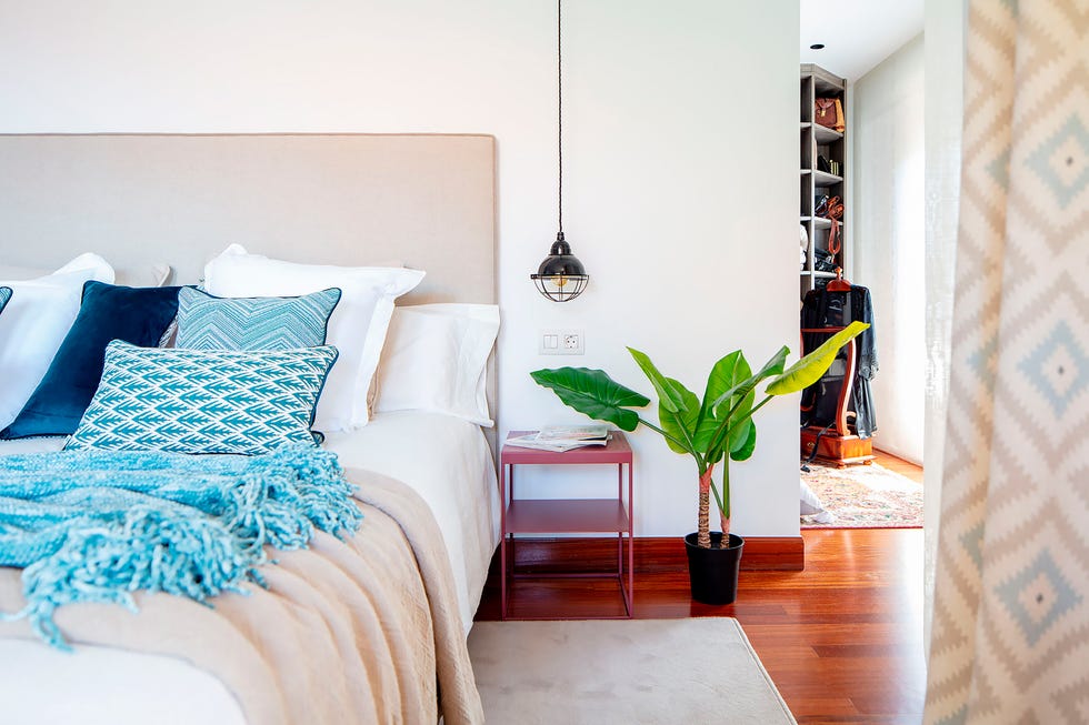 cama con cabecero de color visón y lámparas colgantes industriales