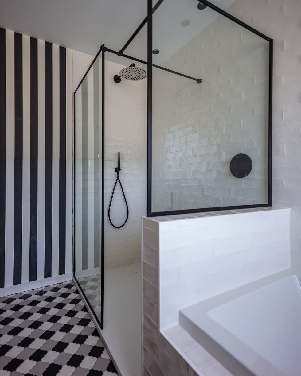 ducha revestida con azulejos tipo metro blancos y paredes con papel pintado a rayas