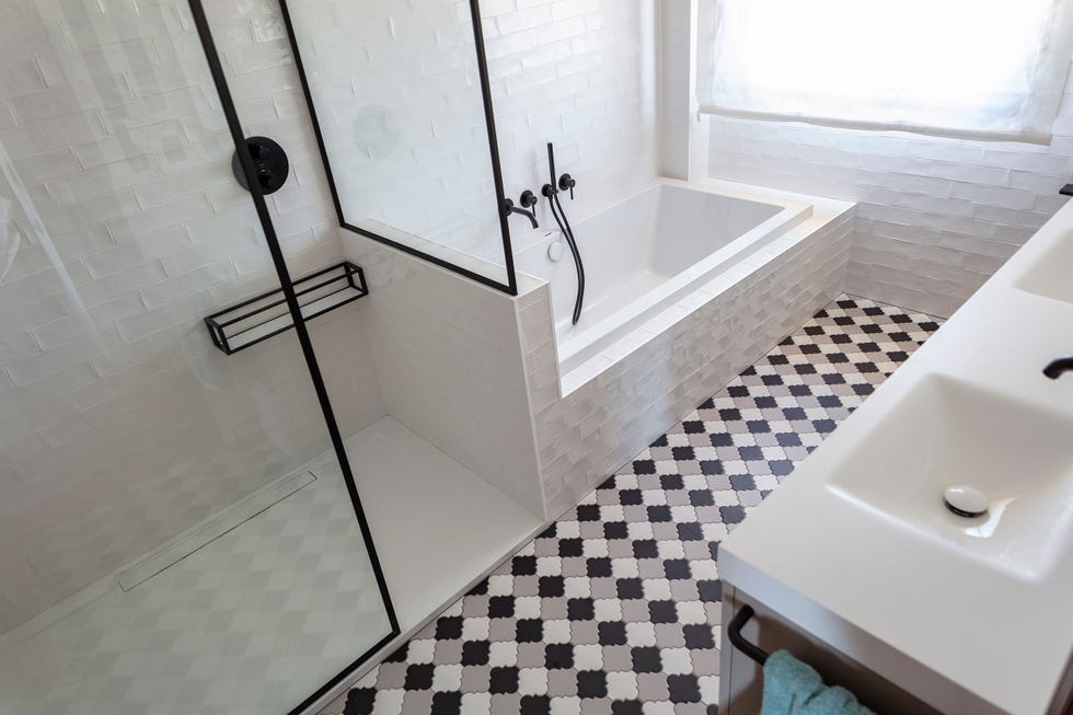 baño con ducha y bañera y suelo de baldosas geométricas
