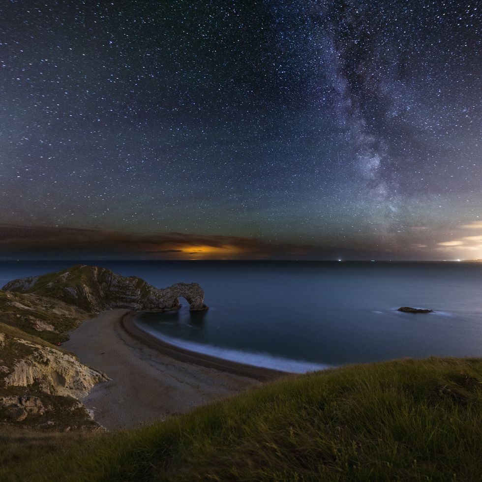 a night photograph taken at durdle door in dorset one of the most recognizable landmark in the uk the photograph is taken at the waters edge and shows crashing waves, curve of the beach and the famous arch way you can also see the milkway