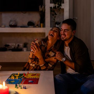 during an energetic crisis, a young couple is playing a ludo game in the dark with lit candles