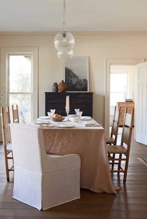 dining table, dusty pink table cloth, wooden dining chairs, white material end chairs, fireplace