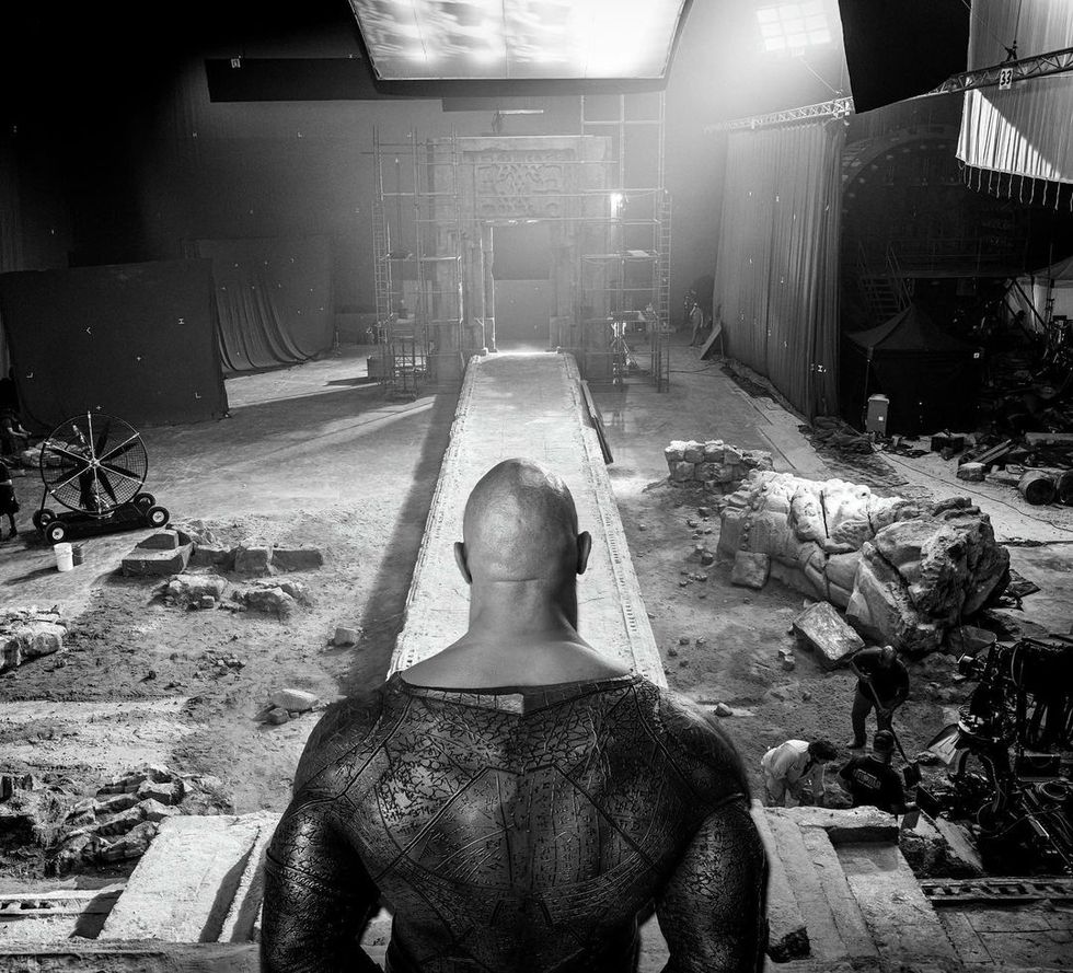 dwayne johnson black adam set photo showing him looking at a destroyed environment