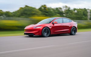 red 2024 tesla model 3 driving down a street