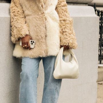 a woman wears a fur coat and carries a purse in a roundup of the best purses on amazon 2023