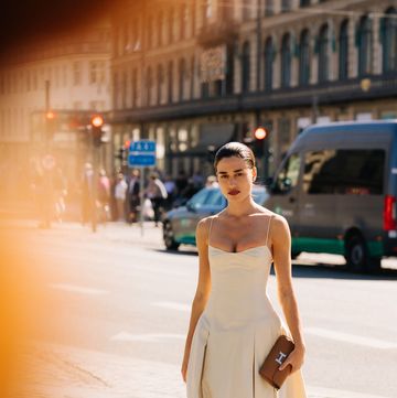 a woman at copenhagen fashion week wears a linen dress while standing on the street to illustrate a guide to the best linen dresses 2023