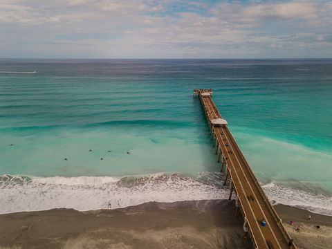 dynamic aerial views of colorful teal ocean waves sweeping across the juno beach florida seashore and pier at mid day in january of 2021