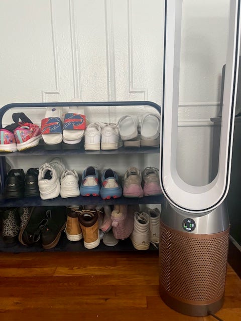 a shelf with shoes and an air purifier tower