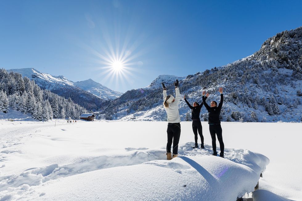 a group of people standing on snow with their arms raised