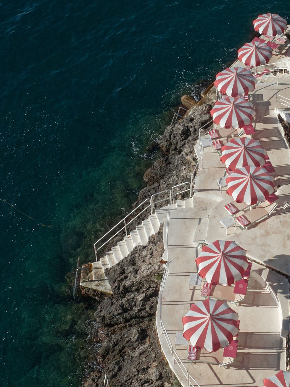 Seaside area with striped umbrellas and steps leading down to the water.